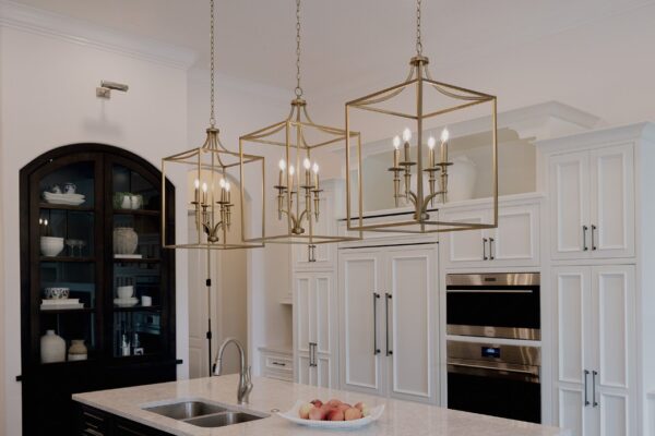 Cream kitchen with an arched black display hutch, brass lantern pendants and double wall ovens &mdash; Windermere kitchen remodel by KBF