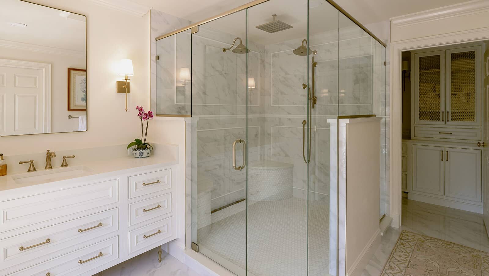 Winter Park bathroom remodeling &mdash; white vanity with brass hardware beside a full-glass double shower
