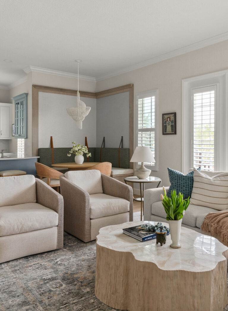 Baldwin Park living room interior design &mdash; swivel chairs and a capiz-shell coffee table, with a banquette dining nook and beaded chandelier beyond