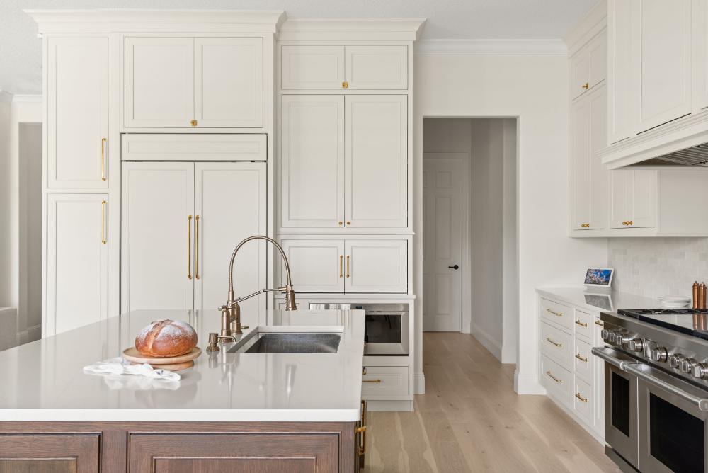 Winter Park kitchen remodel &mdash; cream perimeter cabinetry with brass hardware and a stained-wood island under stone countertops