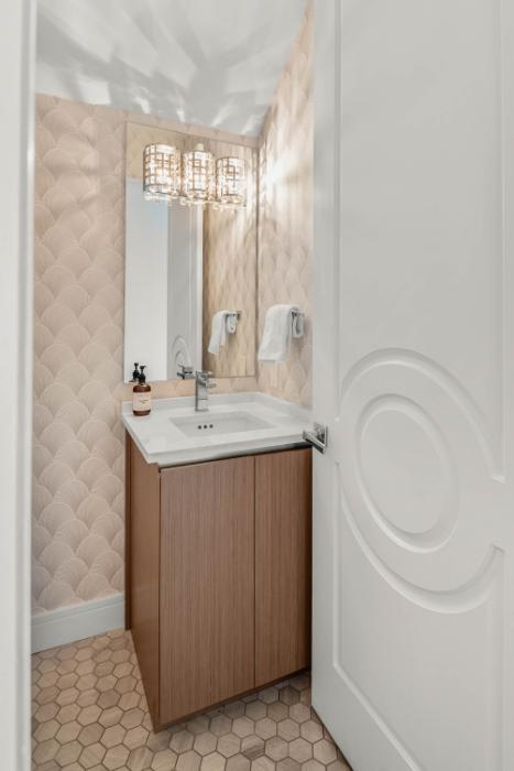 Winter Park townhome powder room &mdash; textured wallcovering, crystal sconce, and compact wood vanity