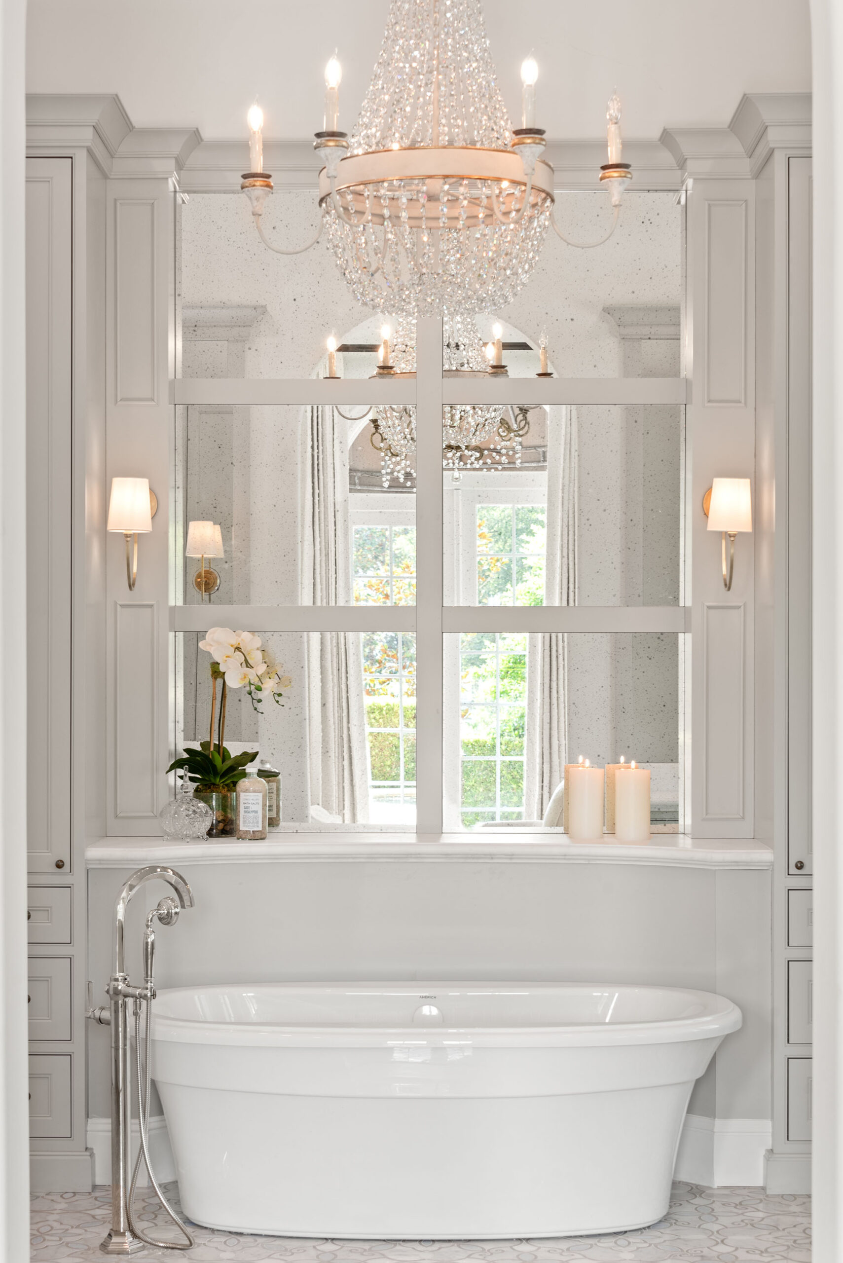 Windermere owners' suite remodel &mdash; the freestanding tub in its mirrored alcove under a beaded chandelier, candles lit on the marble deck