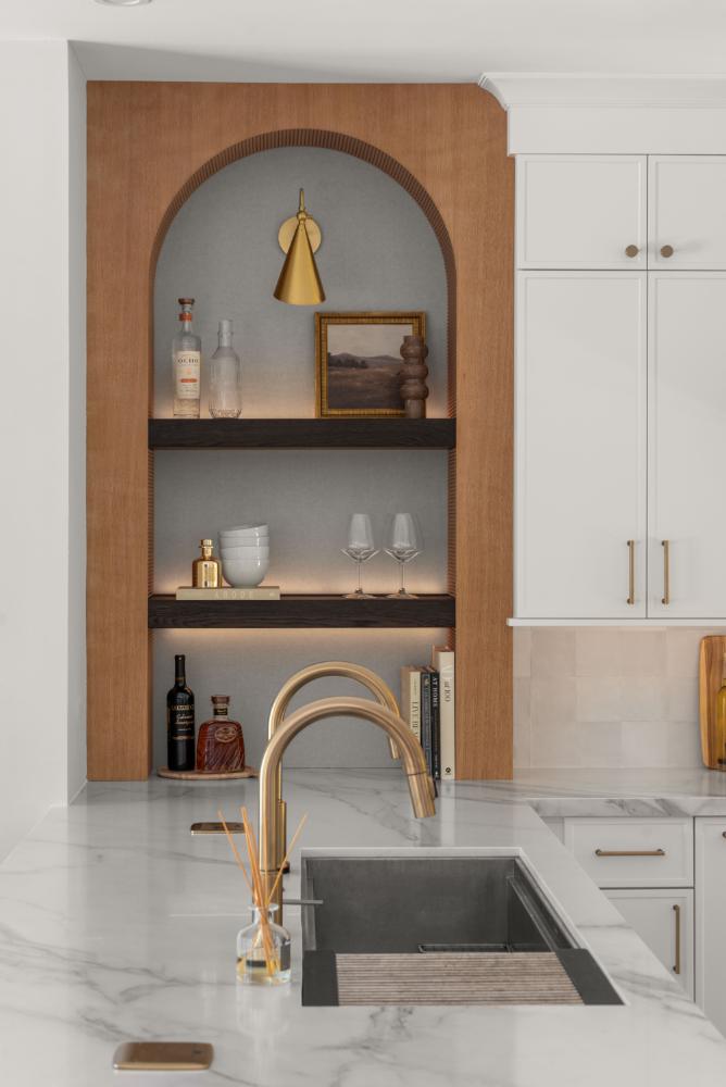Kitchen detail with arched niche shelving, brass pendant light, and gold faucet
