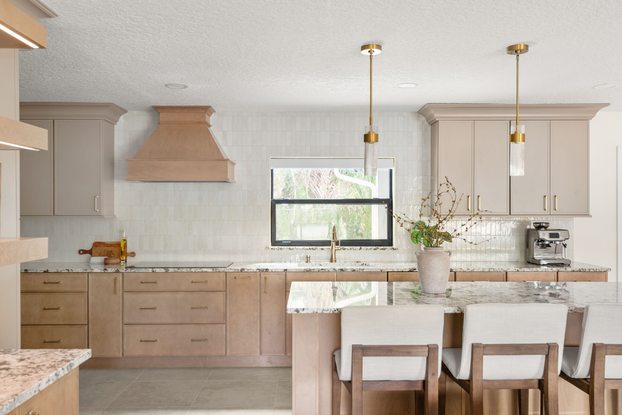 Winter Park whole-home renovation — the remodeled kitchen with white-oak cabinetry, custom hood, and brass pendants