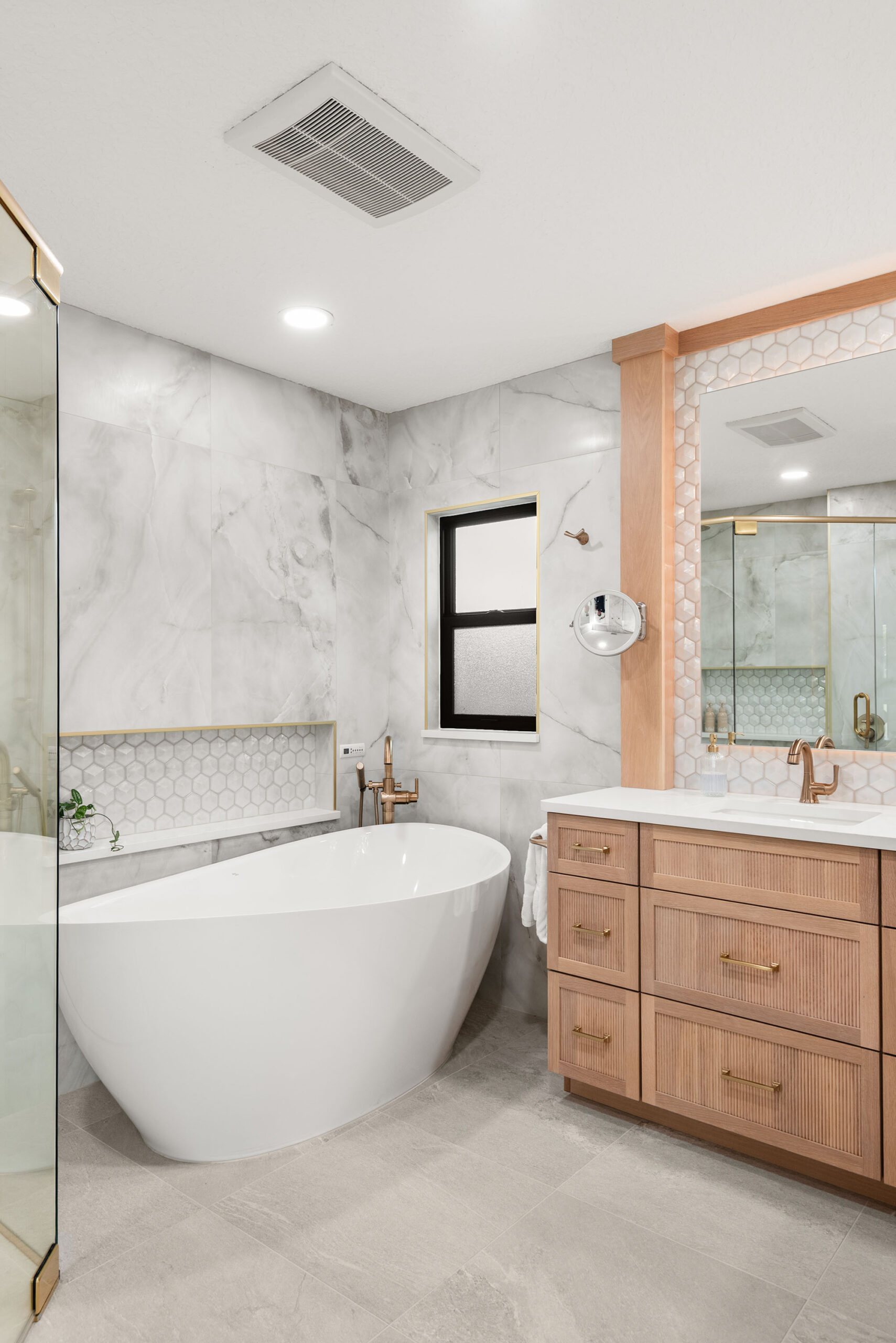 Winter Park whole-home renovation — the primary bath with freestanding tub, fluted white-oak vanity, and hex-tile niche