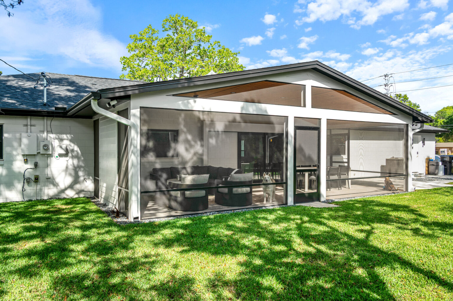 The rear of the Winter Park home after the renovation, with the new covered and screened lanai extending from the back wall over fresh lawn