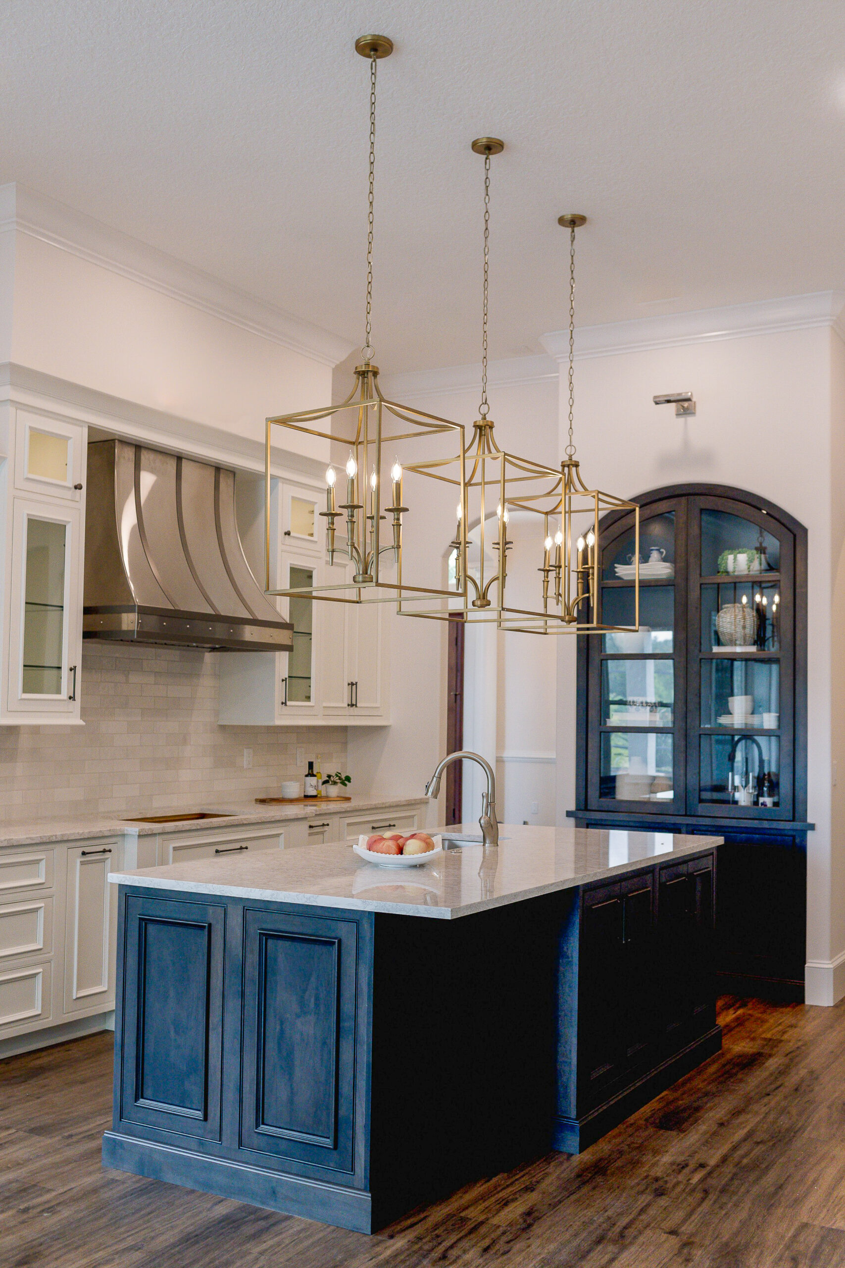 Windermere kitchen remodel with a rich wood island, arched built-in glass-front hutch that has the look of furniture, and brass lantern pendants by KBF Design Gallery