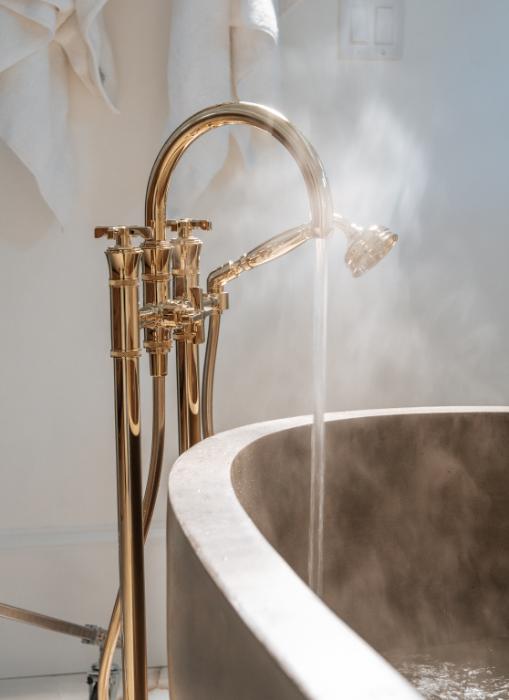 Brass freestanding tub filler pouring into a concrete soaking tub in a Baldwin Park bathroom remodel by KBF Design Gallery
