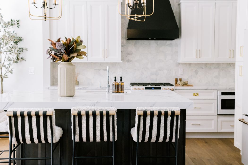 Kitchen remodel in Orlando's Baldwin Park with a black island, marble countertops, and brass lantern pendants by KBF Design Gallery