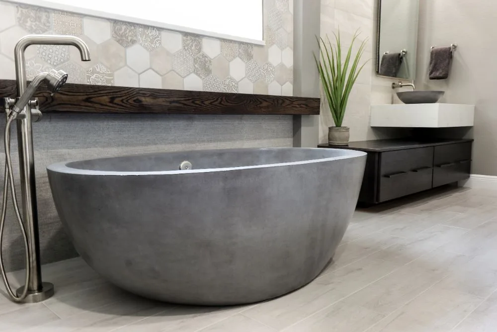 Dr. Phillips master bathroom remodel &mdash; concrete oval freestanding tub under a dark-stained wood mantle beam, hex patchwork feature tile and a floor-mount nickel filler