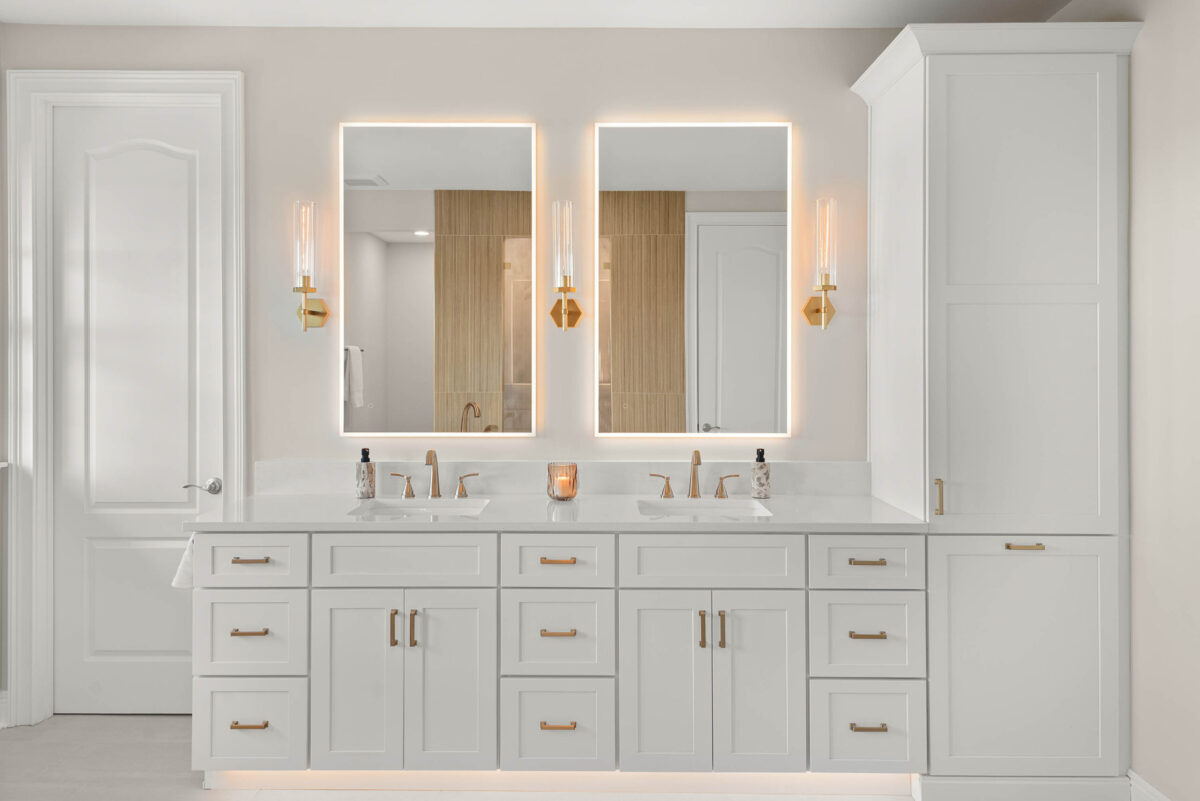 Maitland bathroom remodel with a white double vanity, backlit mirrors, and brass sconces by KBF Design Gallery