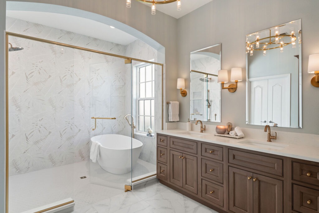 Freestanding soaking tub and arched walk-in shower with palm leaf tile in a Lake Mary bathroom remodel by KBF Design Gallery