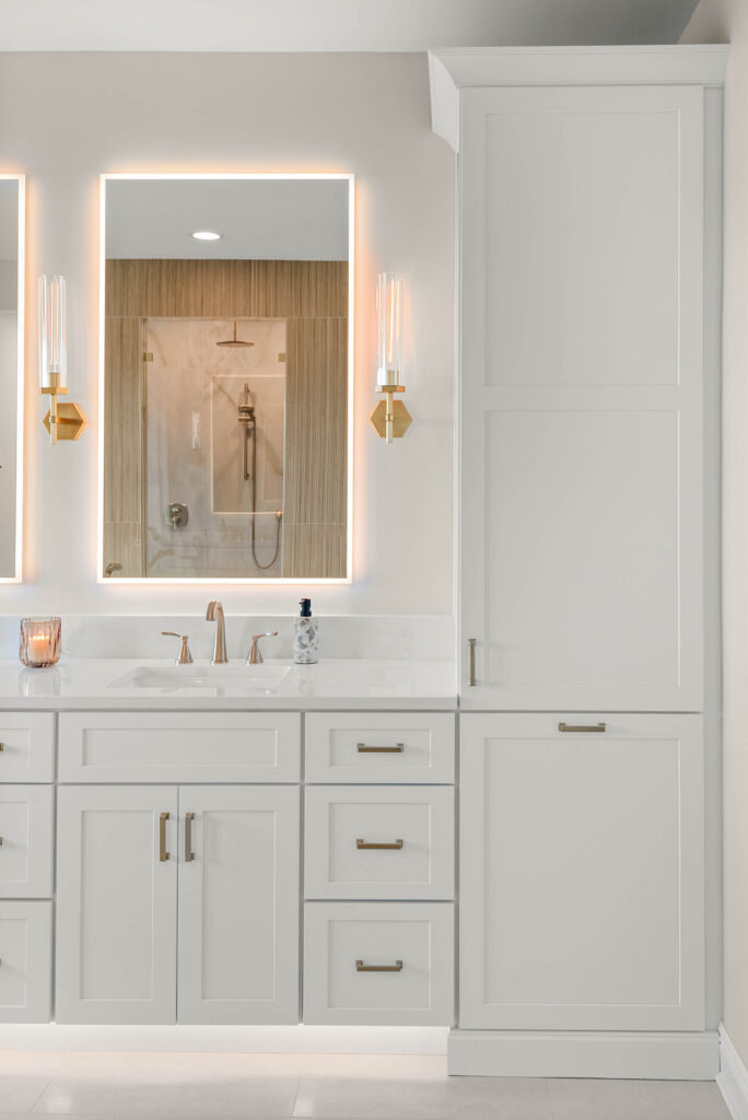 Backlit mirror, sconces, and custom white cabinetry in a Lake Mary bathroom remodeled by KBF Design Gallery