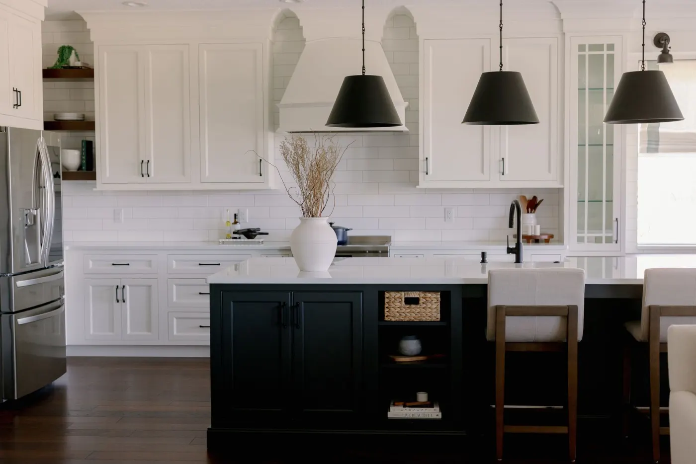The kitchen after completion &mdash; white perimeter cabinetry, black island, black cone pendants