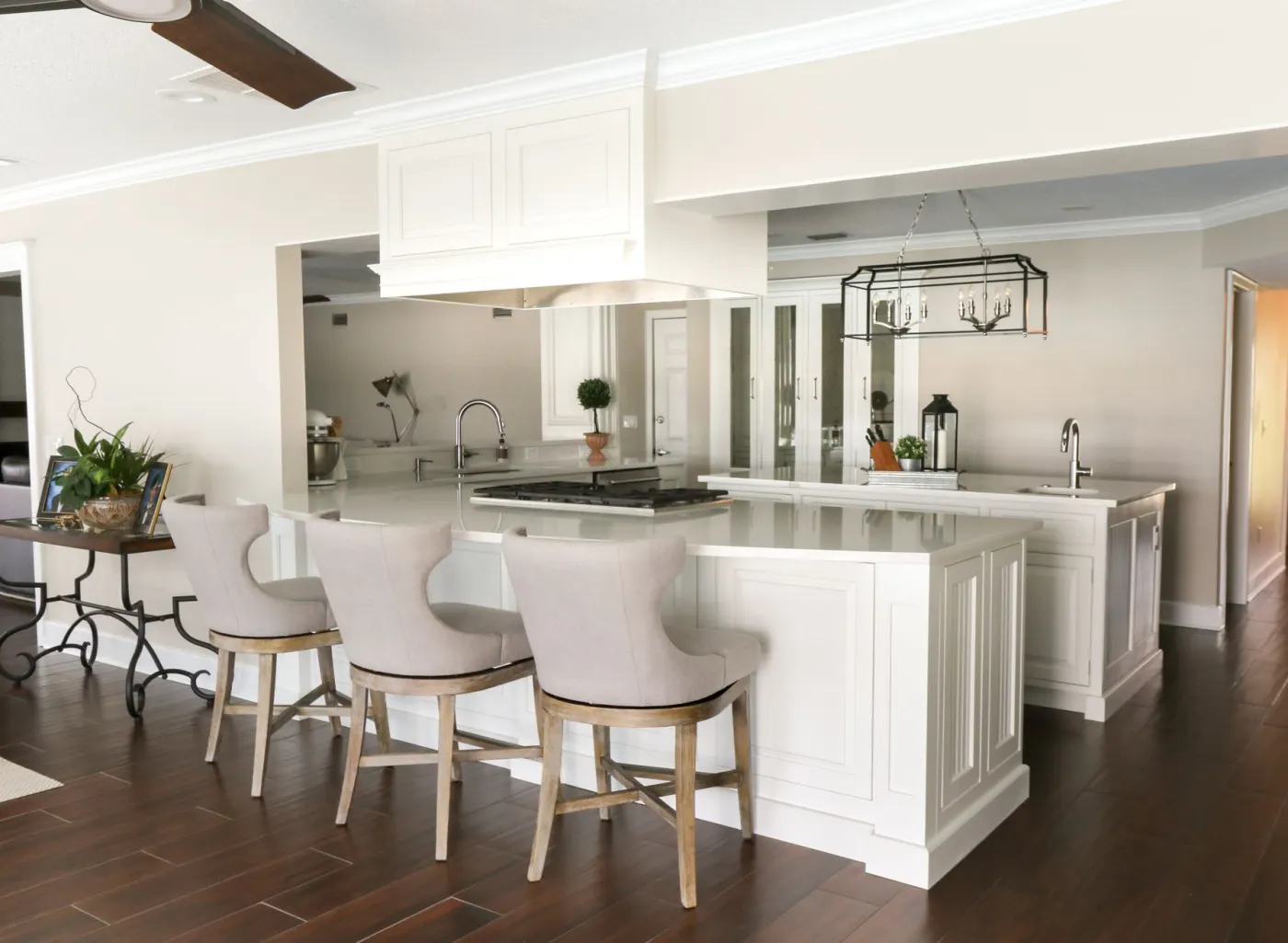 A completed KBF kitchen: cream cabinetry, a marble-topped island, upholstered stools and an iron lantern pendant