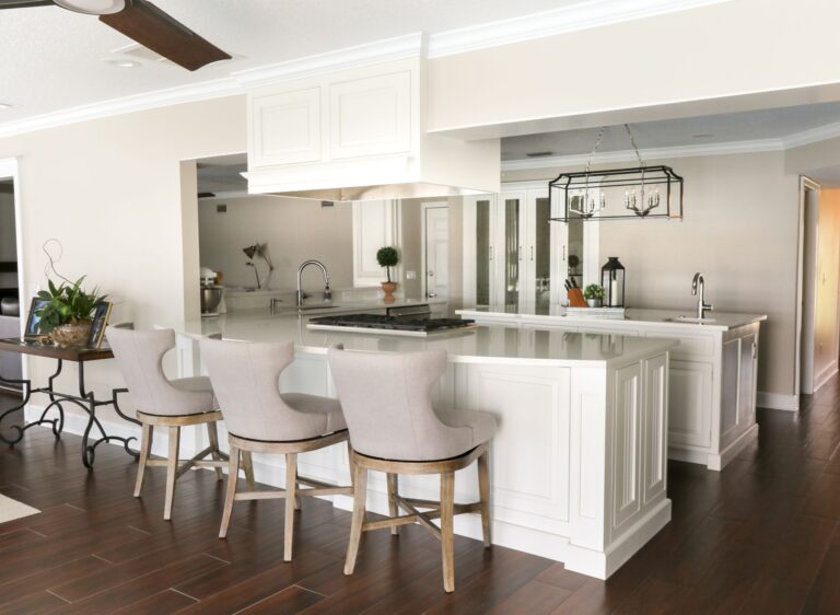 The Winter Garden kitchen &mdash; cream cabinetry, marble-topped island with upholstered stools, and an iron lantern pendant, photographed on completion