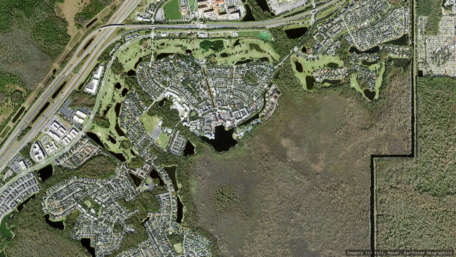 Satellite view of Celebration, Florida from neighborhood altitude &mdash; the pattern-book village grid around downtown Market Street and its lake, ringed by golf fairways and preserve wetland. Imagery &copy; Esri, Maxar, Earthstar Geographics