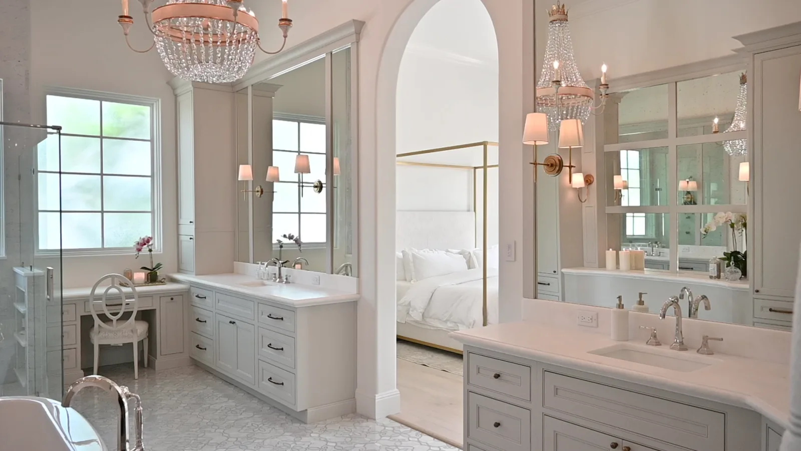 A completed KBF primary bathroom in Windermere, Florida: freestanding tub beside a chrome floor-mount filler, ivory double vanities with marble tops, beaded chandeliers and a mosaic marble floor