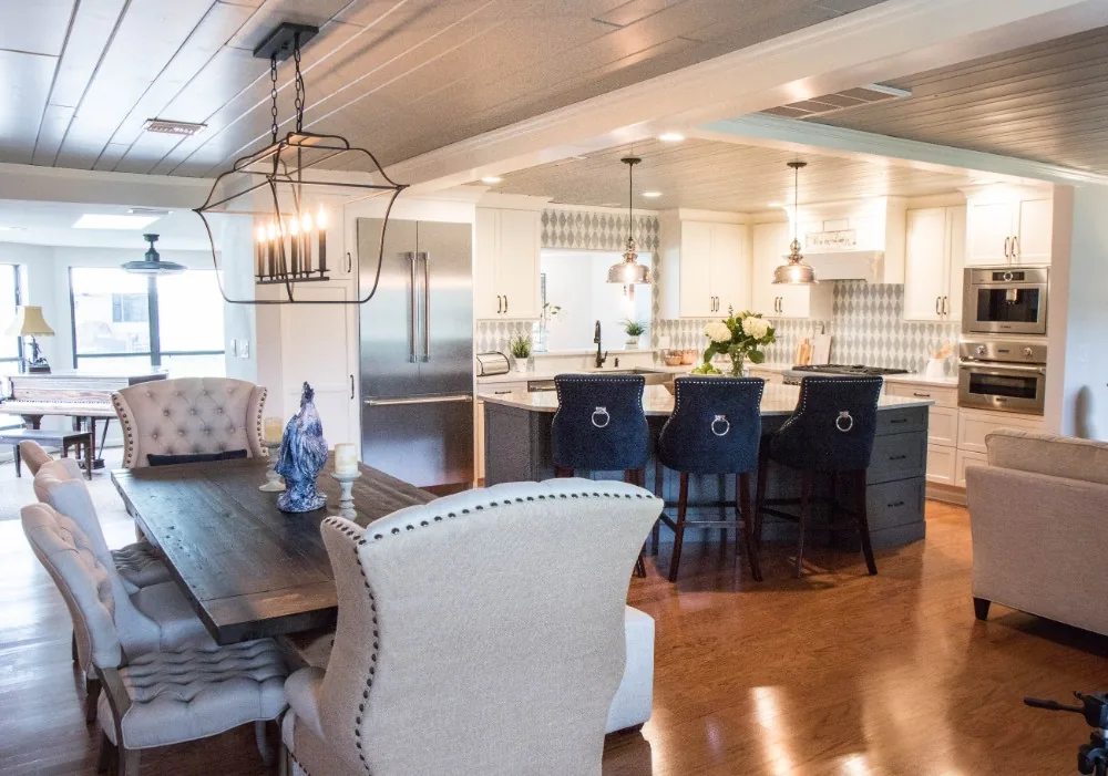 The remodeled DeLand home after two walls came down: an open-concept space where the kitchen island, dining table, and living area share one room under painted plank ceilings