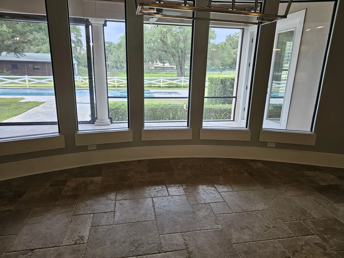 The home before the remodel — a curved bay window with dated travertine flooring