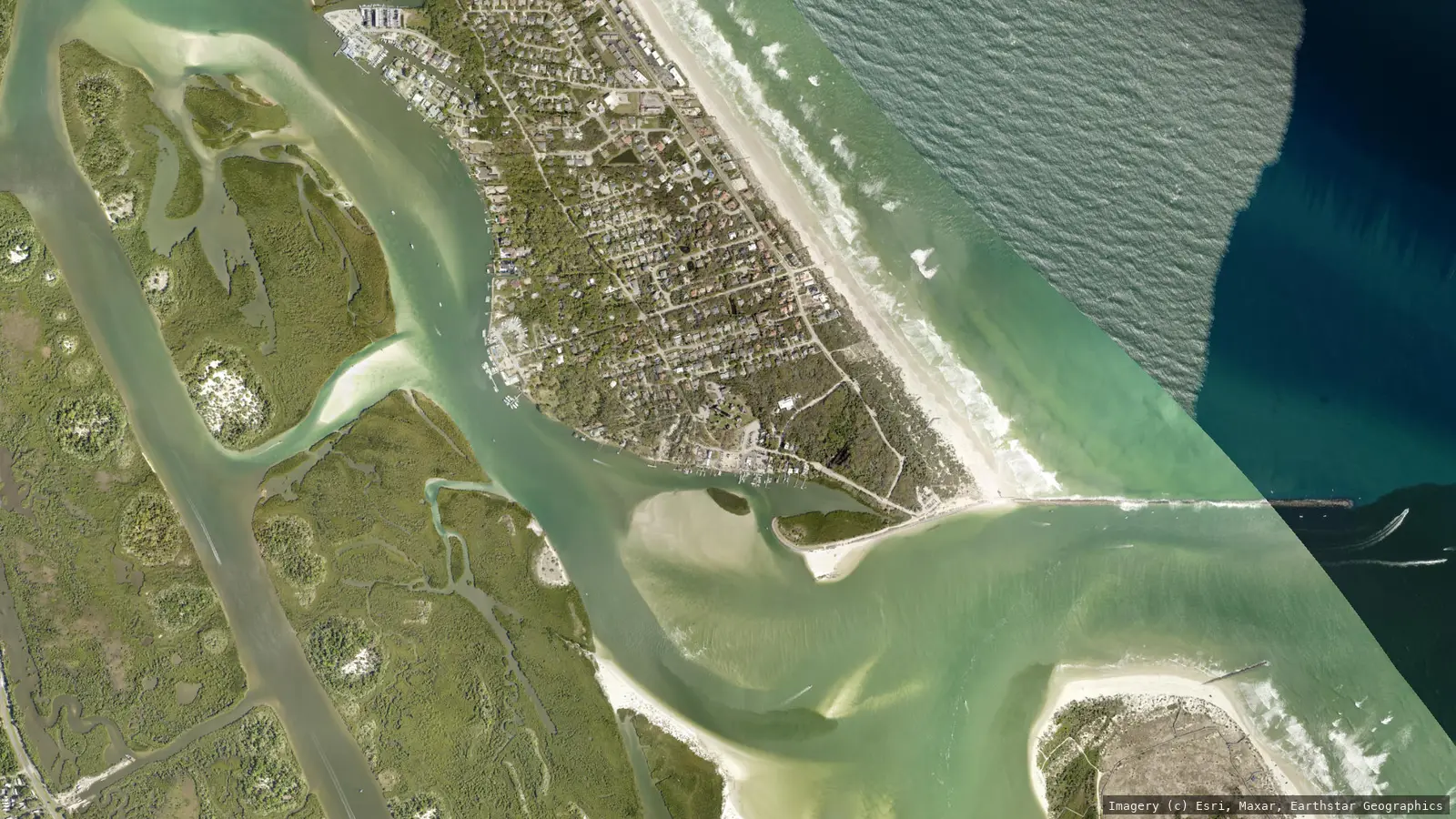 Satellite view of Ponce de Leon Inlet from neighborhood altitude &mdash; the Town of Ponce Inlet's streets on the peninsula between the Halifax River and the Atlantic, the jetties at the inlet mouth, and the north end of New Smyrna Beach across the channel. Imagery &copy; Esri, Maxar, Earthstar Geographics