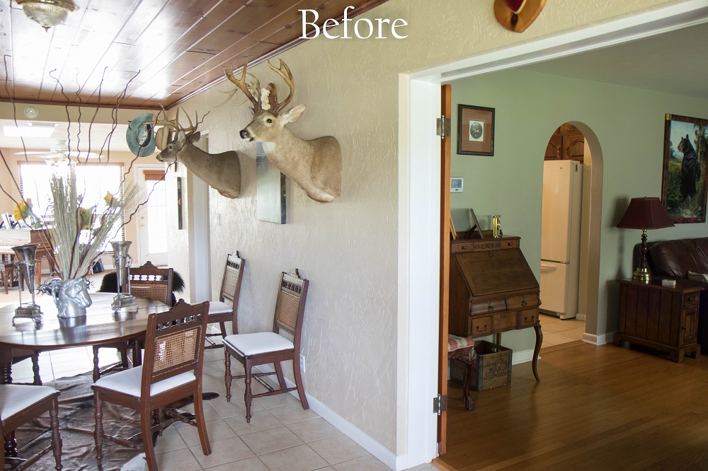 The dining room before remodeling, closed off from the kitchen by a load-bearing wall, with a wood-paneled ceiling and a cased doorway into the next room
