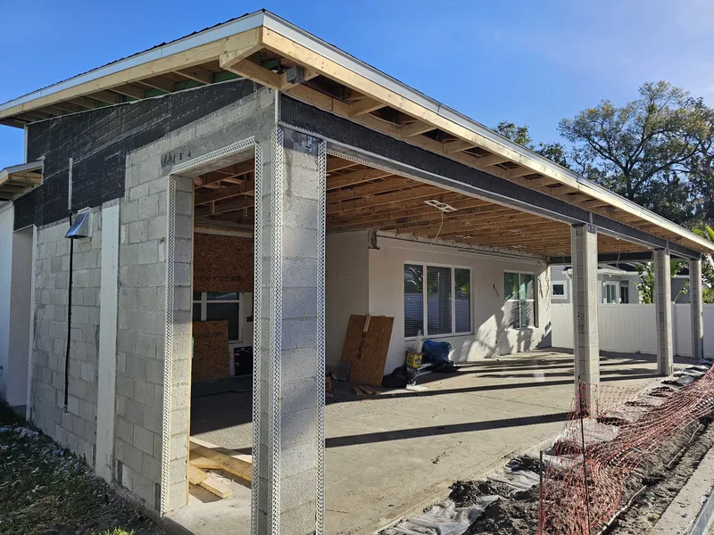 The same addition at shell stage &mdash; masonry block walls, engineered stick-built truss framing, and dry-in roof