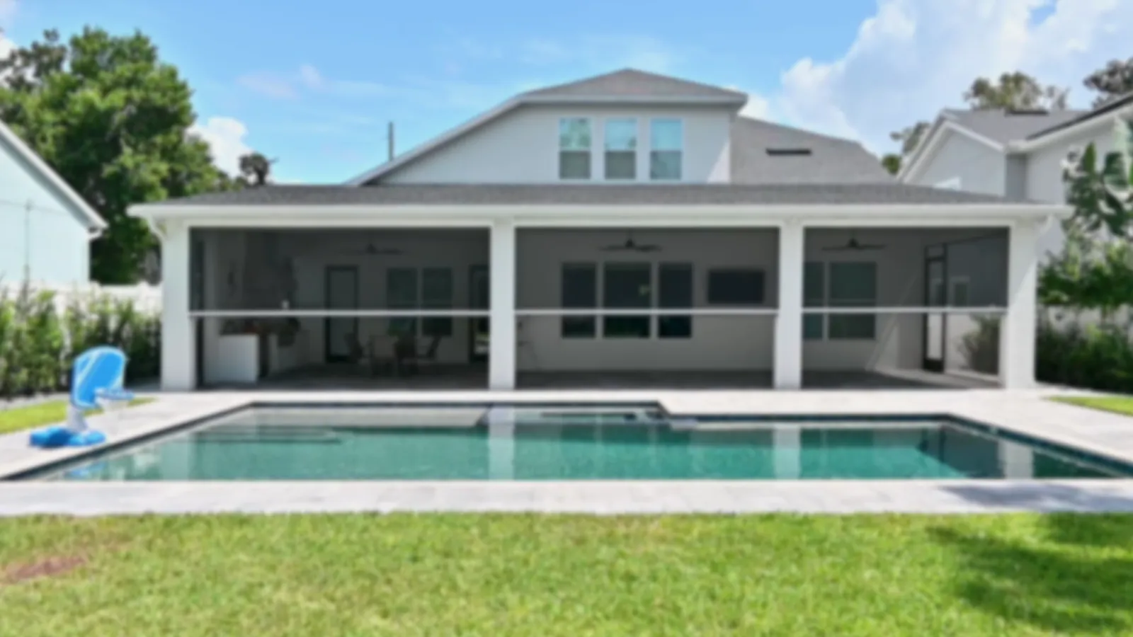 Rear elevation of a completed covered-living and summer-kitchen addition in Orlando &mdash; engineered colonnade, pool surround, and paver deck