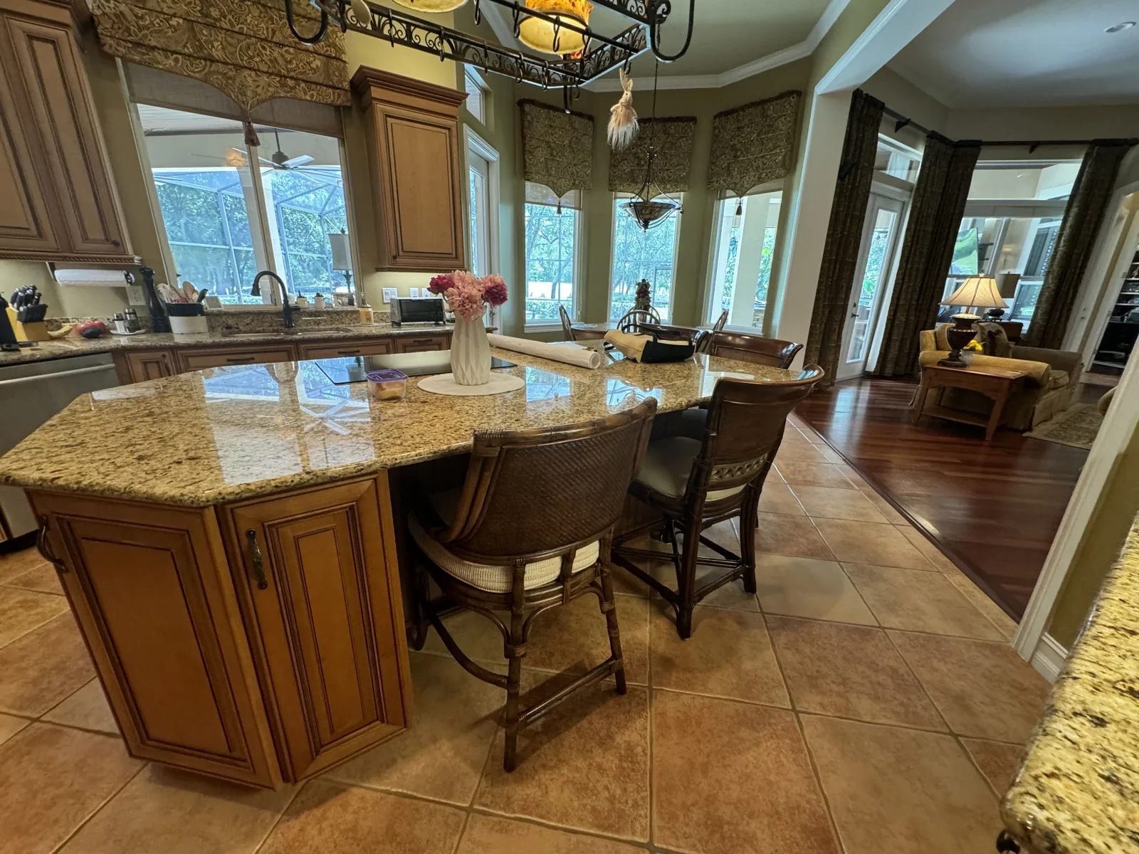 The kitchen island before the remodel: tan granite with wicker bar stools, looking toward the breakfast-nook windows