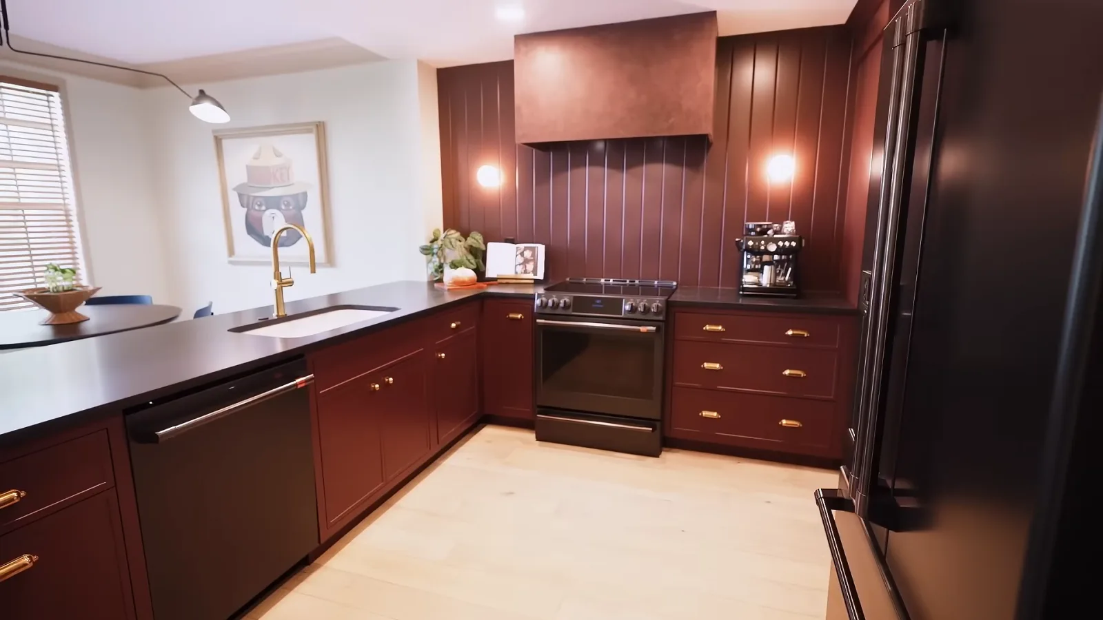 A completed KBF whole-home remodel in Celebration, Florida: the townhome’s oxblood-paneled kitchen with brass cup pulls, honed black stone counters and a plaster-finished hood