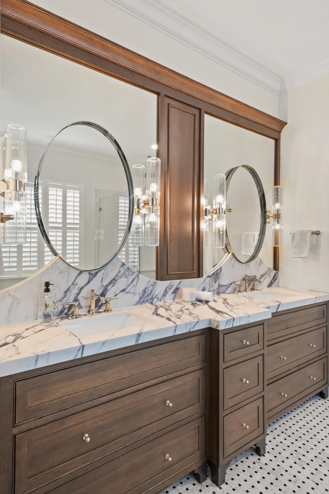 Winter Park bath remodel &mdash; wood double vanity with dramatic marble backsplash and oval mirrors