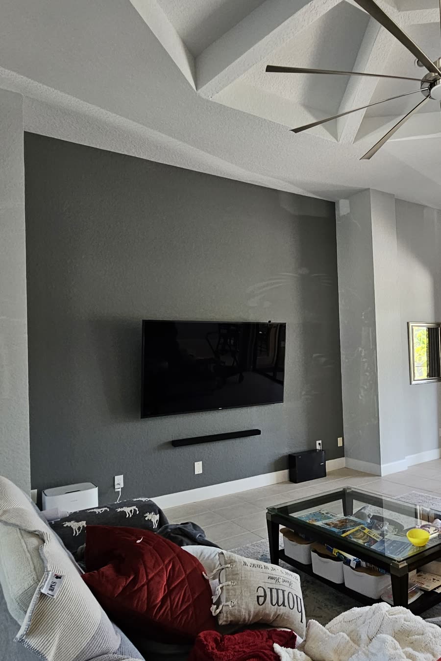 Orlando family room before remodeling, with a television on a grey painted accent wall above a soundbar and beige tile flooring