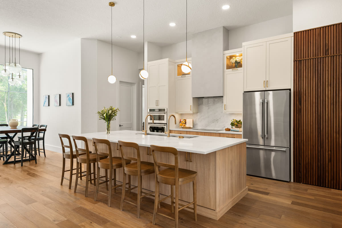 Remodeled Orlando kitchen with a pale wood island seating five, cream floor-to-ceiling cabinetry and wide-plank wood floors running through to the dining area
