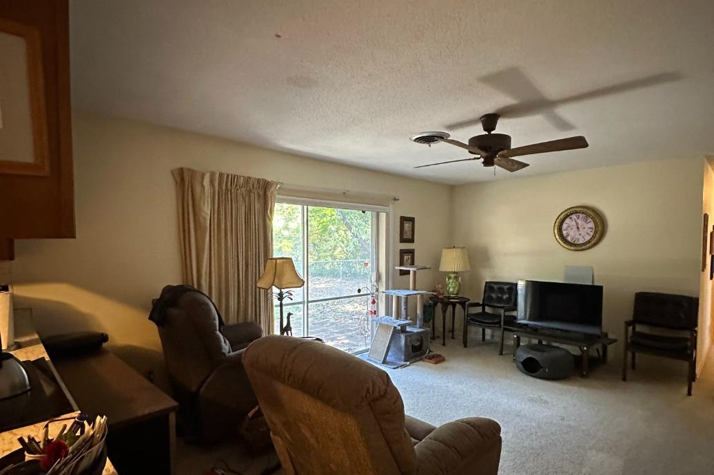 The original living room before the remodel, with a sliding glass door to the back yard at left, carpet, recliners and a television on the far wall