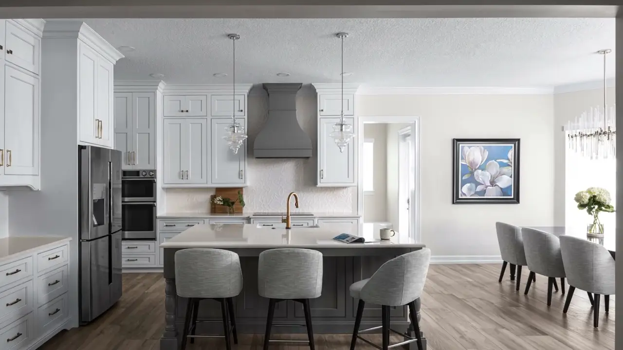 The finished kitchen: white cabinetry, a plaster hood, quartz island, wood floors.