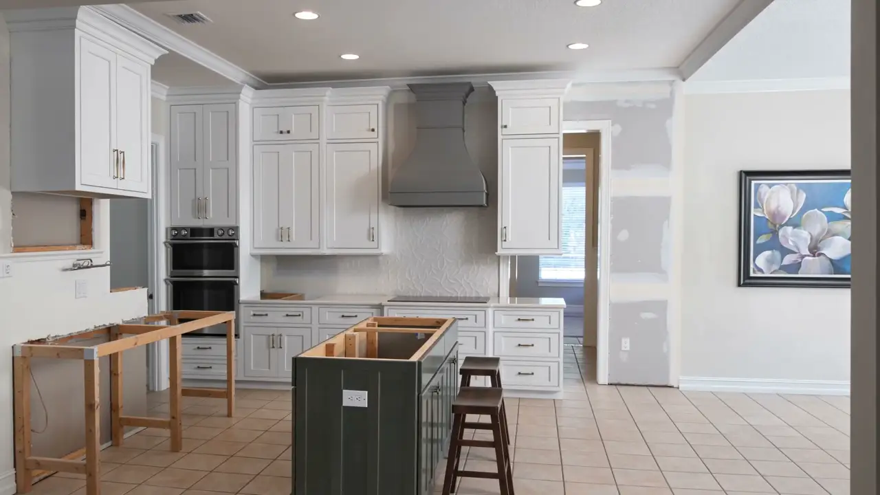 The same kitchen mid-build: cabinetry set, island framing open, drywall patched.